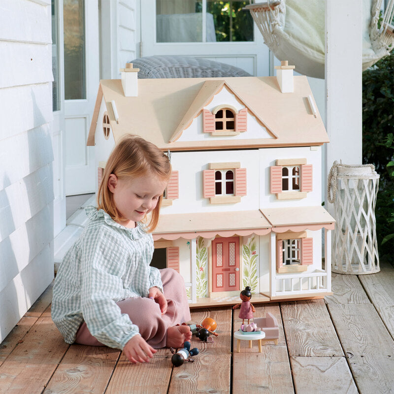 little girl sitting on a verandah with a Large White Tender Leaf Toys dolls house