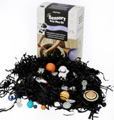 Sensory play kit with planets and stars on a black shredded paper base, featuring a box labeled 'Sensory Play Kit' in the background.